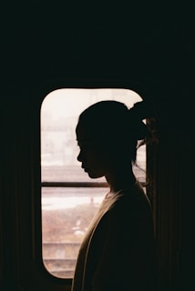 Mulher com expressão pensativa olhando pela janela