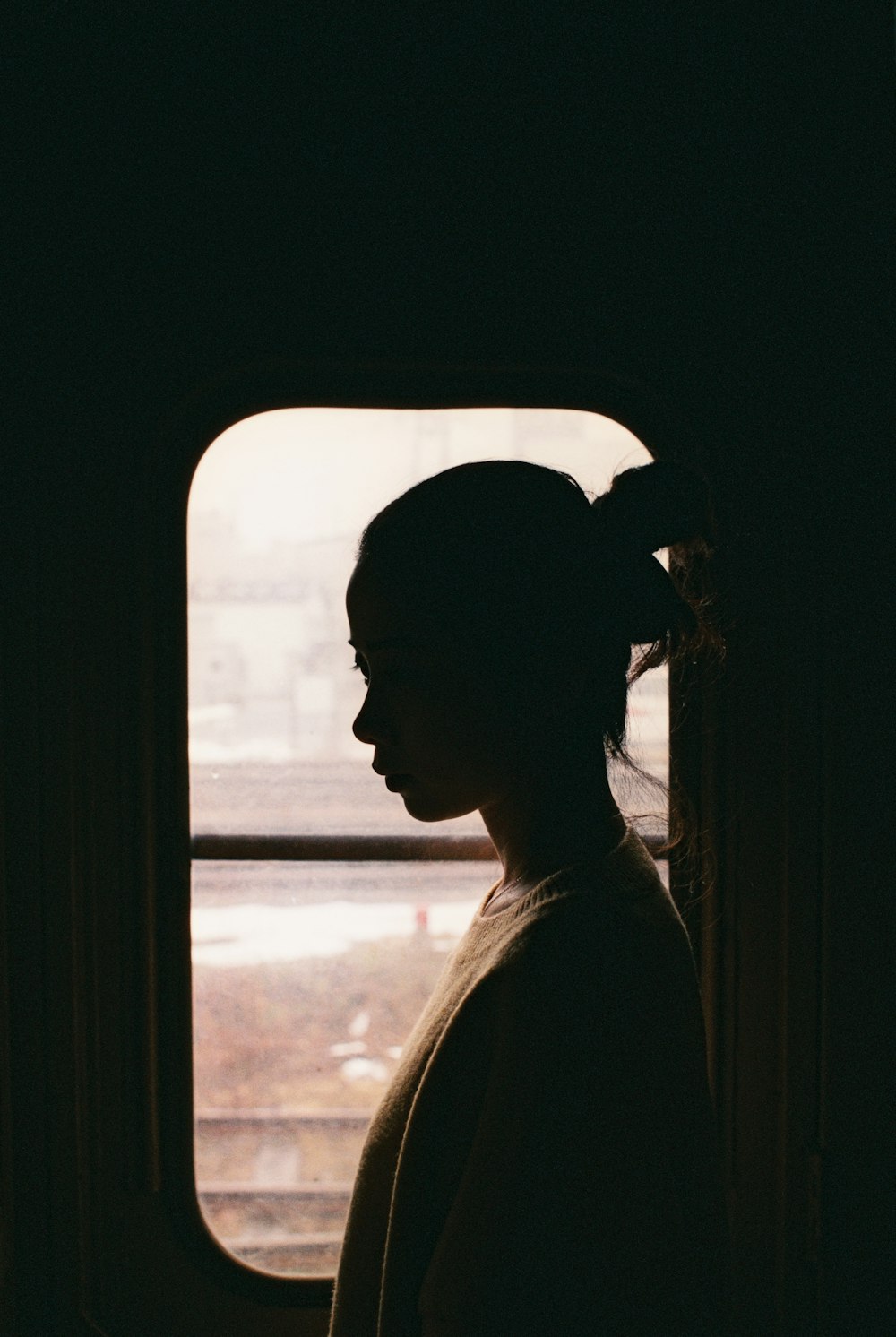 woman in white shirt looking at the window during daytime