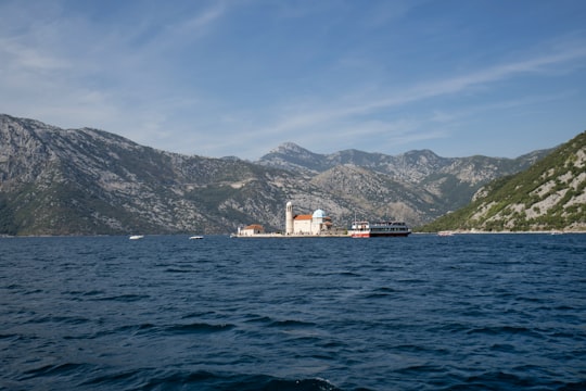 white and brown building near body of water during daytime in Our Lady of the Rocks Montenegro