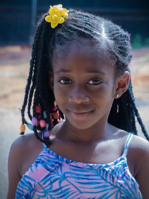 Young girl smiling with colorful beads braided into her hair.