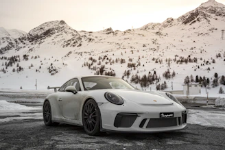 A sleek sedan parked against a backdrop of snow-capped Himachal mountains.