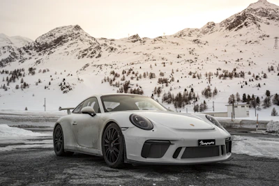 A sleek sedan parked against a backdrop of snow-capped Himachal mountains.