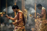 man in brown and beige traditional dress holding yellow string lights