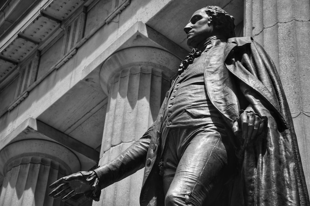 grayscale photo of man in jacket and pants statue