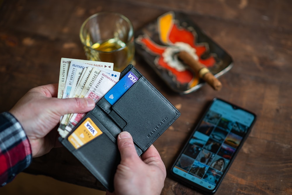 person holding black leather bifold wallet