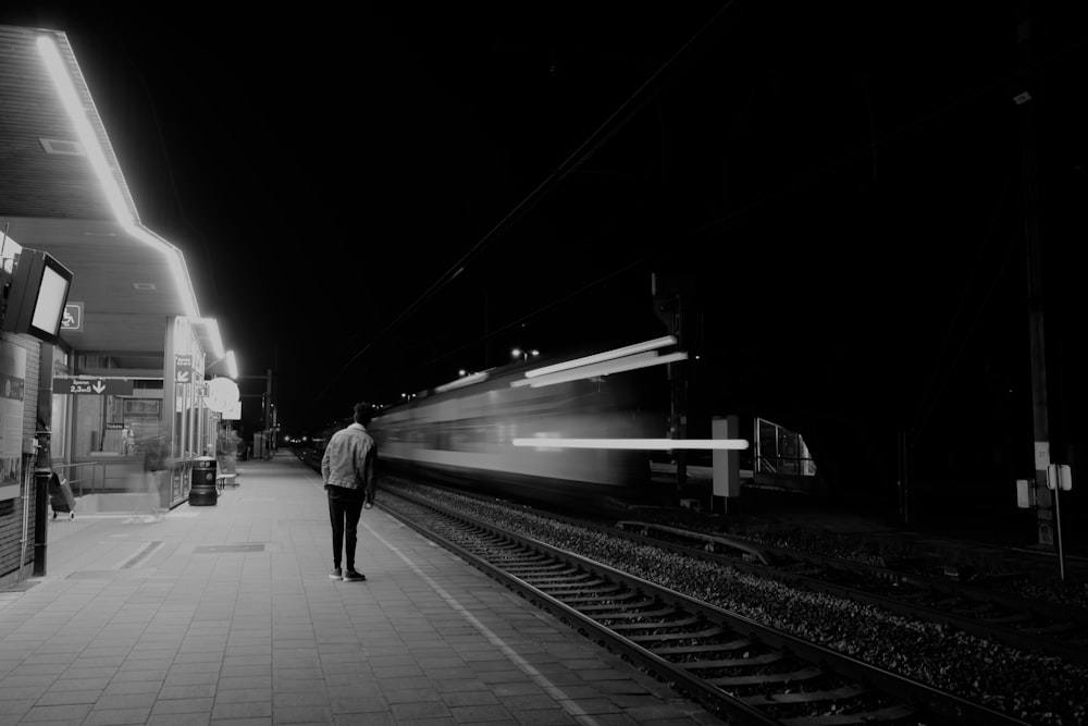 grayscale photo of people walking on train station