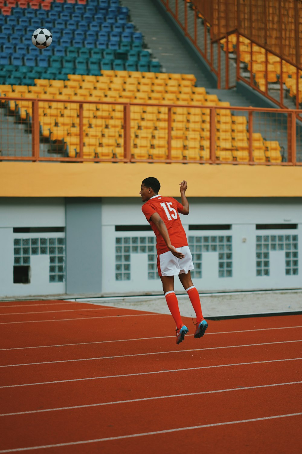 man in red jersey shirt and white shorts running on track field during daytime