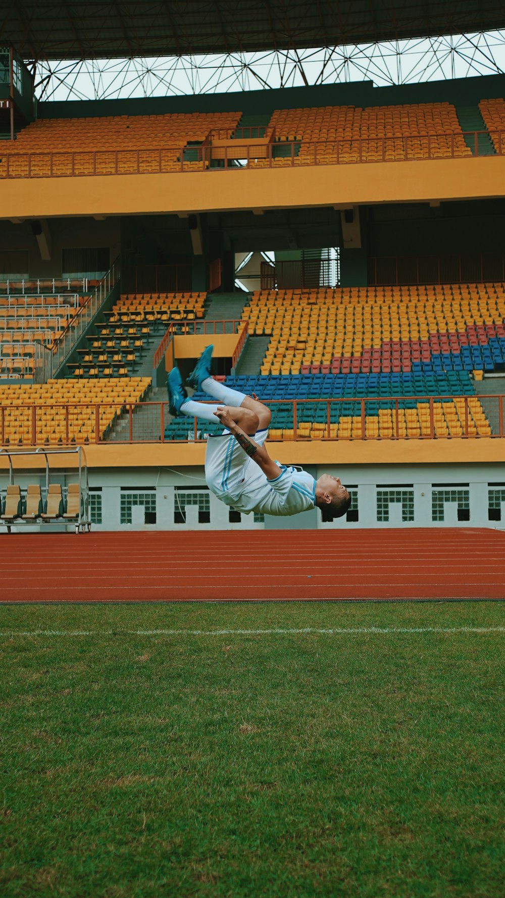 man in white shirt and blue pants sitting on stadium bench