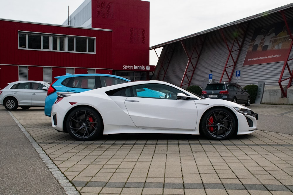 white coupe parked beside red building