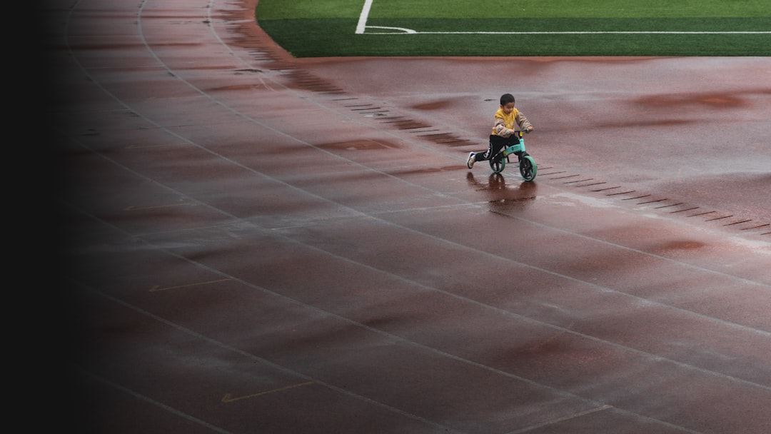 boy in blue shirt riding bicycle on track field during daytime