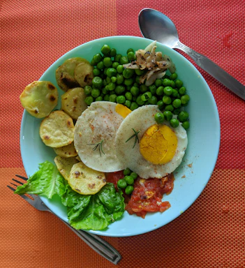 A vibrant plate showing a stuffed omelette with arrachera and chistorra, accompanied by fresh fruit and a cup of steaming coffee served in a rustic clay mug.