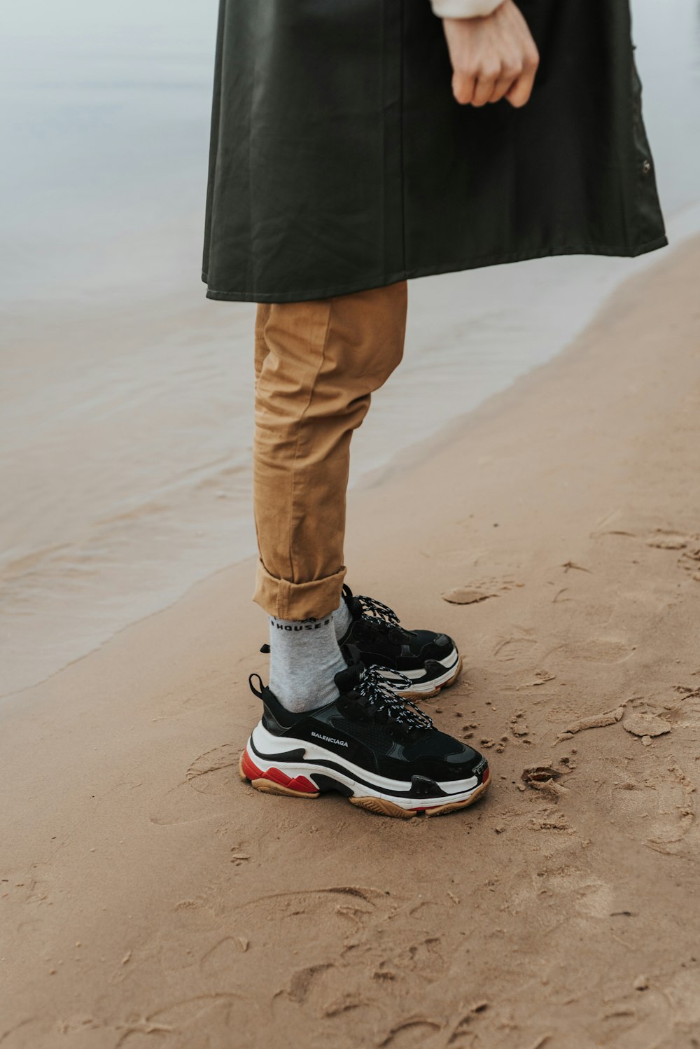 person in black and white nike sneakers standing on brown sand during daytime