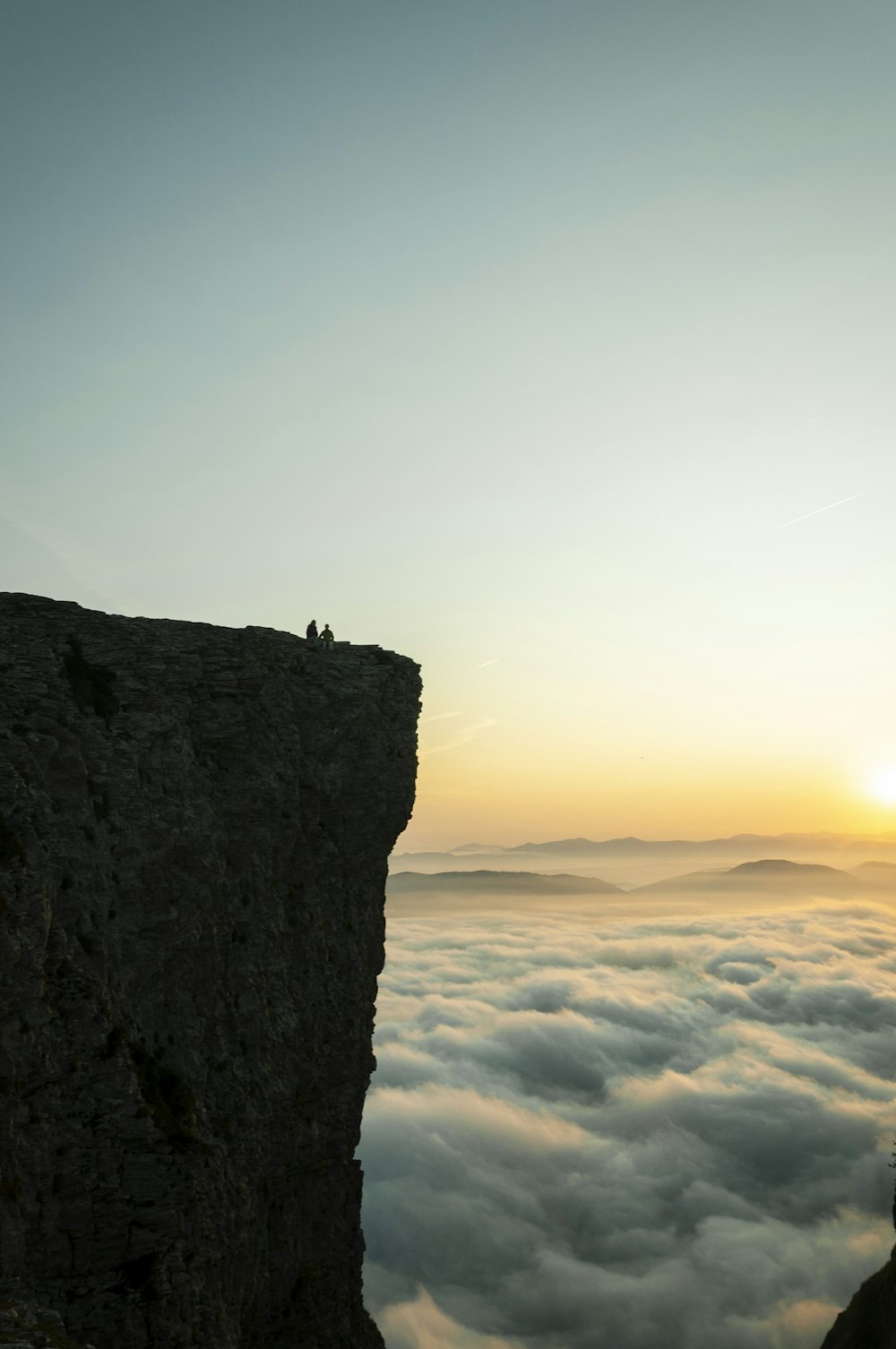 silhouette of person standing on rock formation during sunset