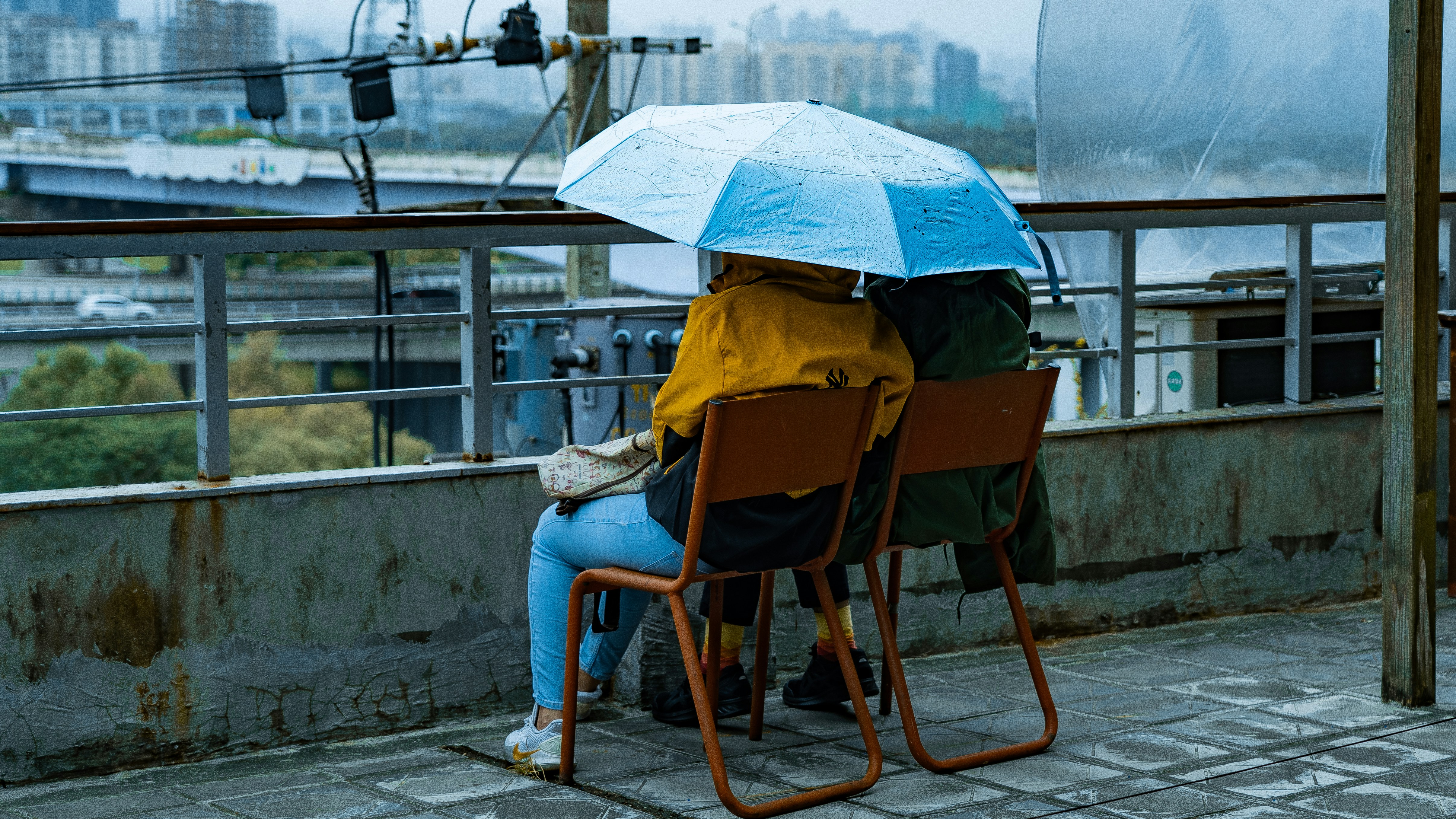 woman in blue denim jeans sitting on brown wooden chair holding umbrella
