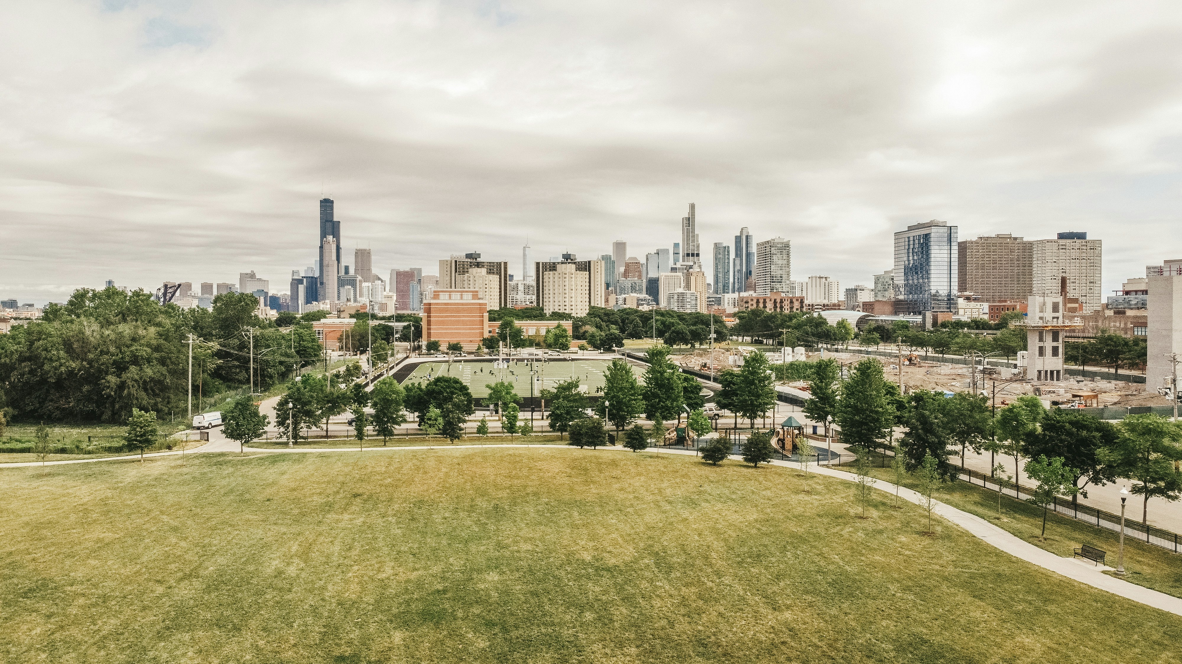green grass field near city buildings during daytime