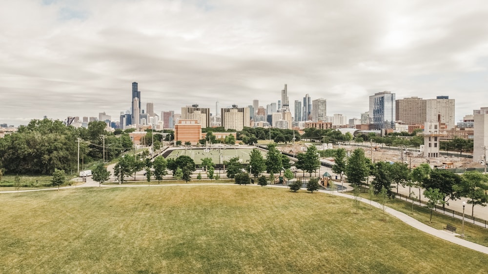 green grass field near city buildings during daytime