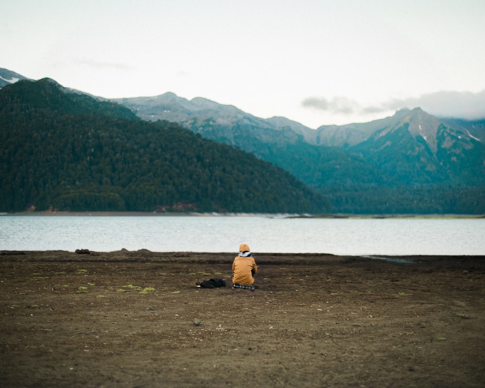 2 person sitting on brown grass field near body of water during daytime