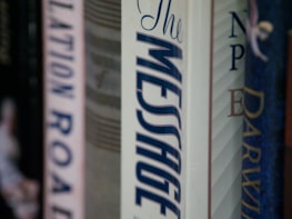A row of books on a shelf focuses on the spine of a book titled 'The Message'. The titles of other books are partially visible, providing a sense of a personal library or a collection.