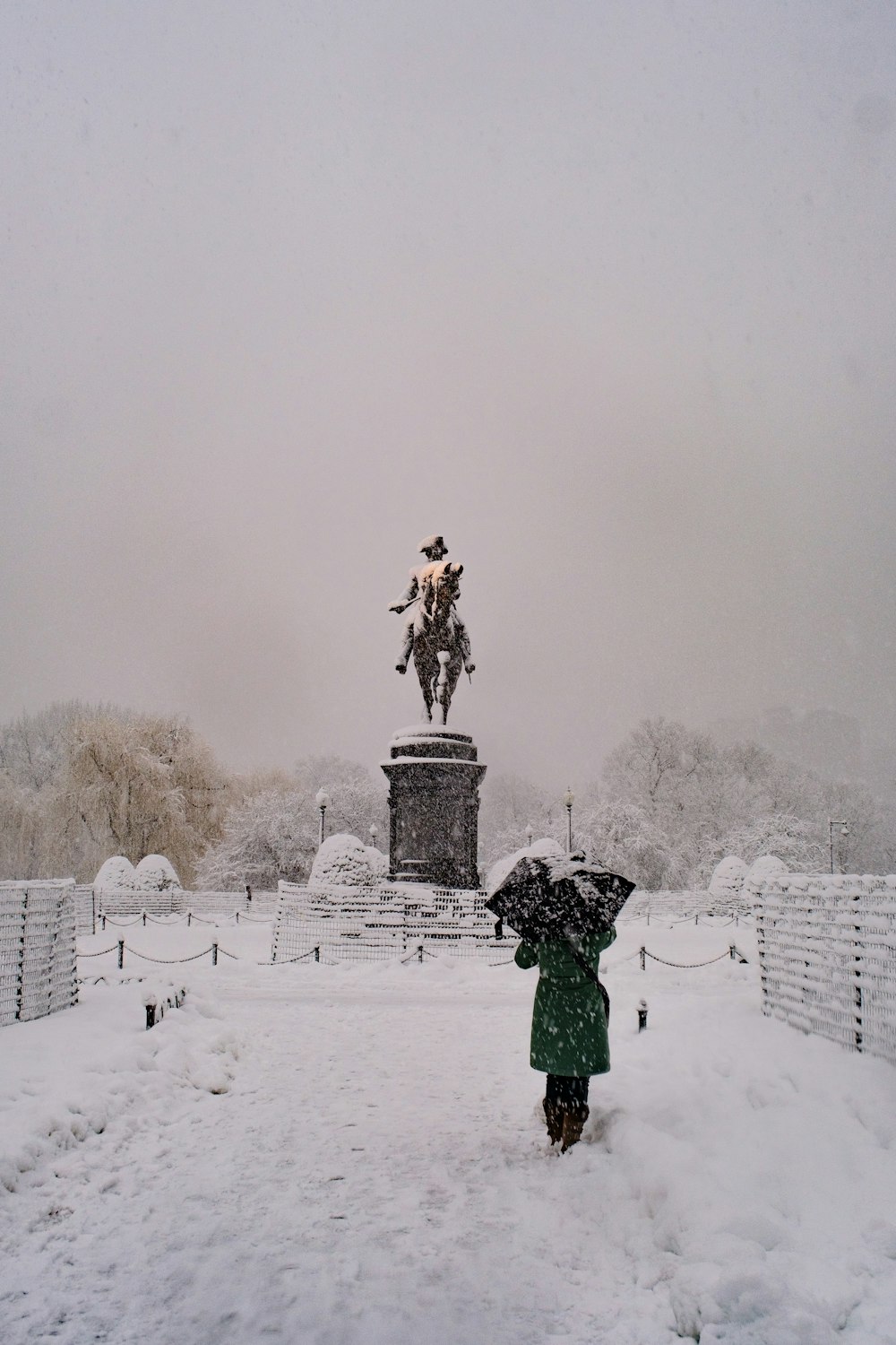 person in green jacket standing on snow covered field during daytime