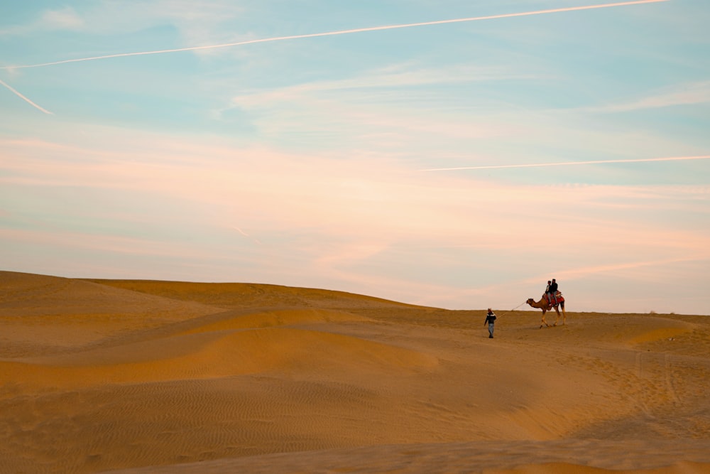 Gente montando camello en el desierto durante el día