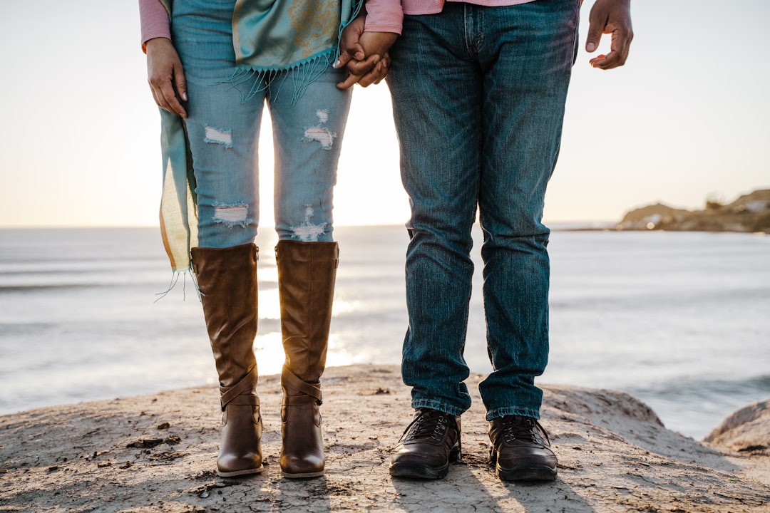 man in blue denim jeans and woman in blue denim jeans walking on beach during daytime