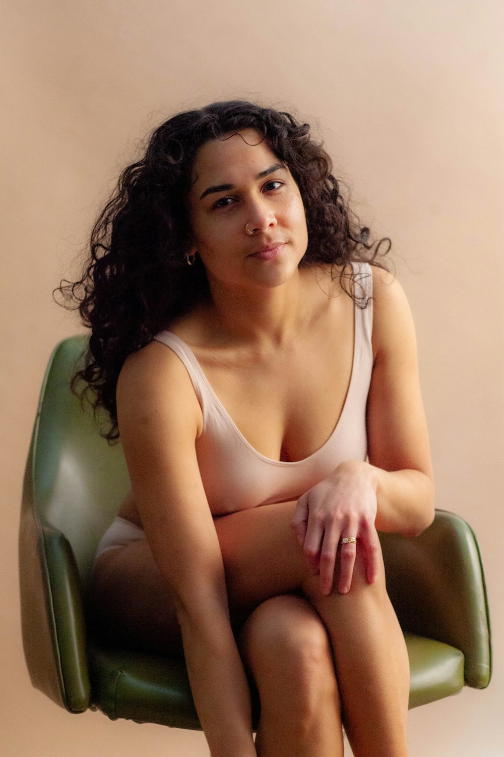 woman in white tank top sitting on green leather chair