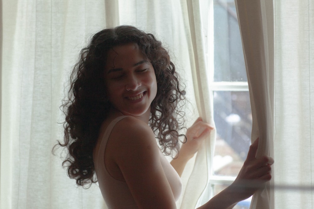 woman in white tank top sitting on white bed