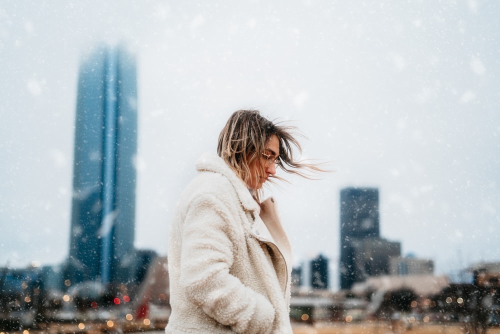 Mujer con bata blanca de pie en el suelo cubierto de nieve durante el día