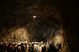 A group exploring a mysterious underground cave with headlamps lighting the way.