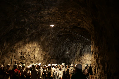 A group exploring a mysterious underground cave with headlamps lighting the way.