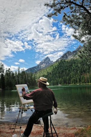 man in red shirt and brown hat standing on boat on lake during daytime