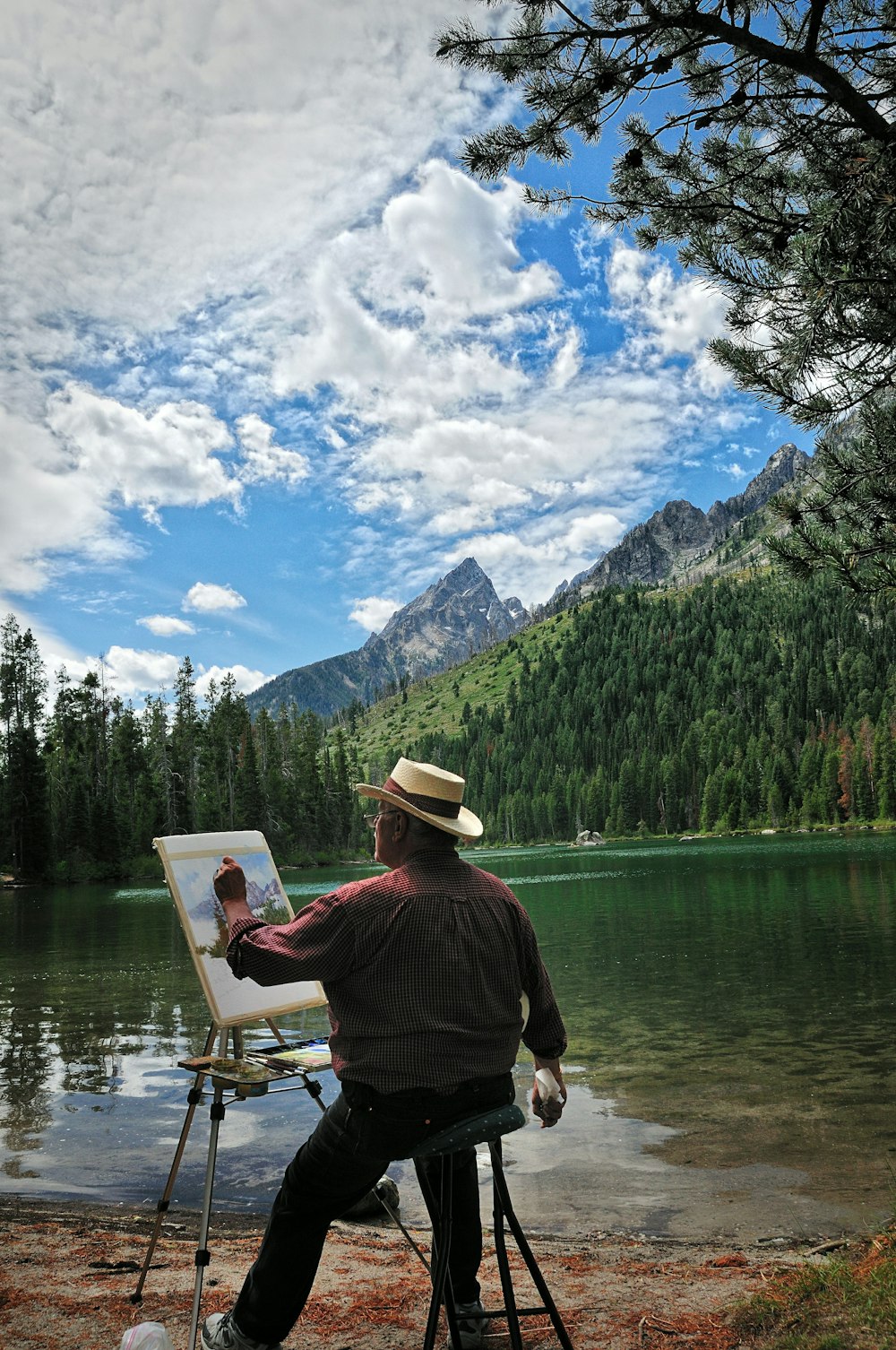 uomo in camicia rossa e cappello marrone in piedi sulla barca sul lago durante il giorno