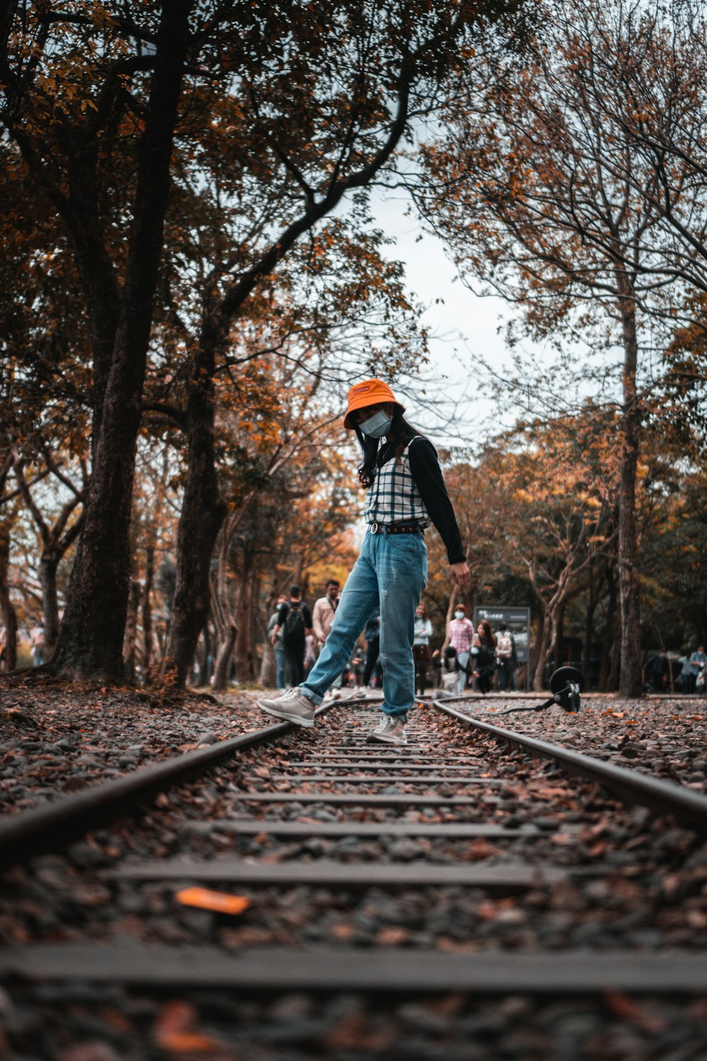 man in black jacket and blue denim jeans standing on train rail during daytime