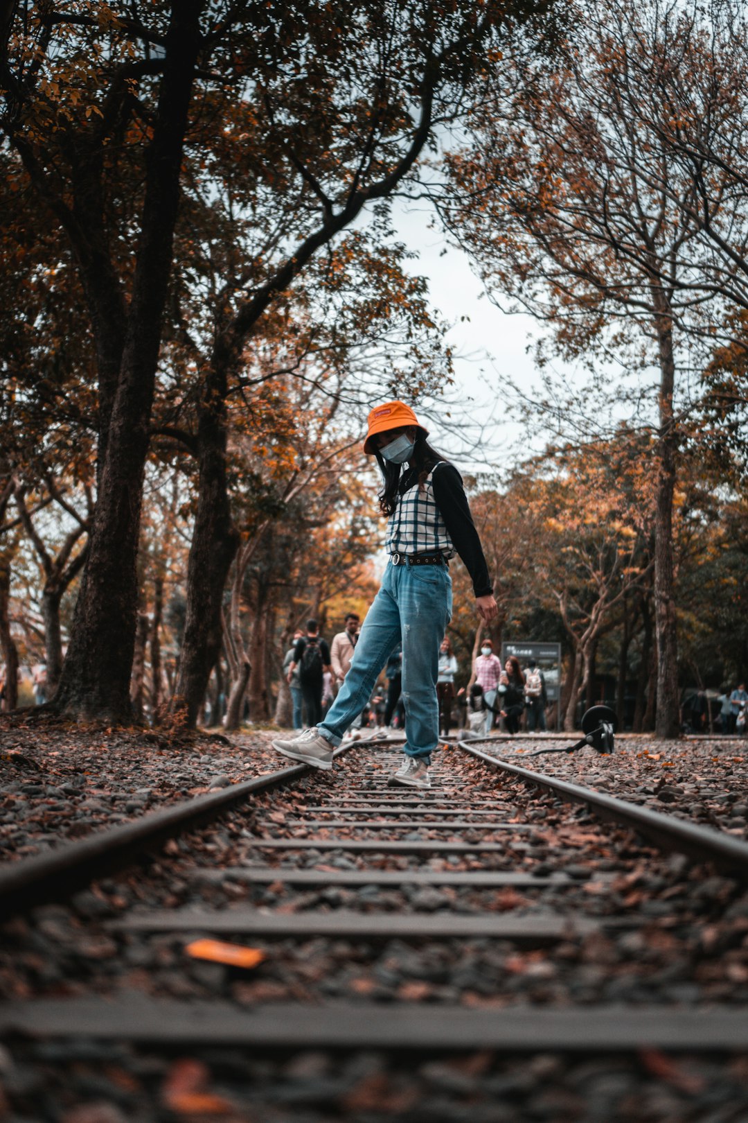 man in black jacket and blue denim jeans standing on train rail during daytime