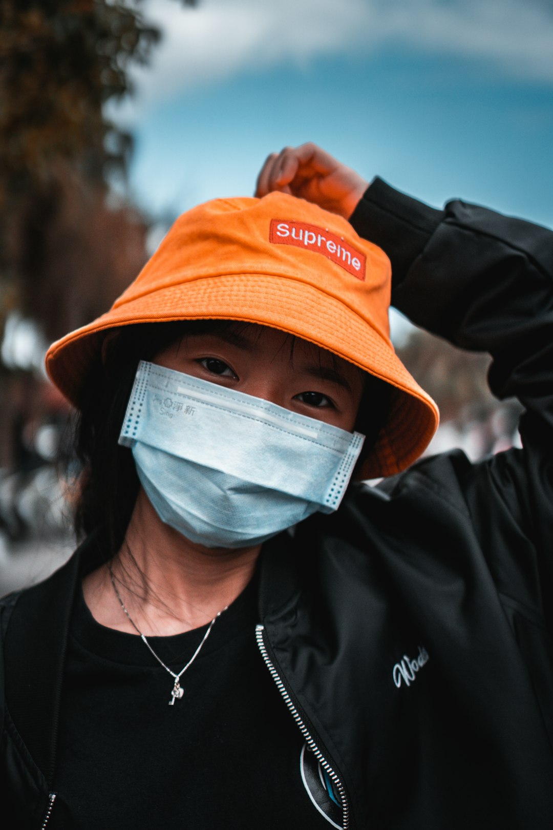 man in orange and white fitted cap and black jacket