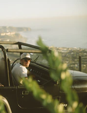 man in white dress shirt sitting on green car during daytime