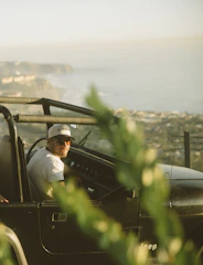 man in white dress shirt sitting on green car during daytime