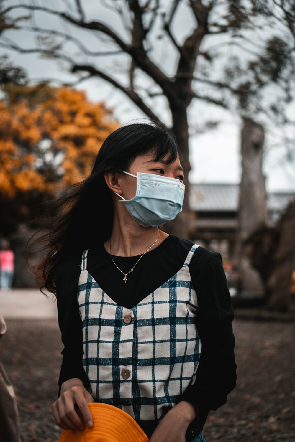 woman in black and white plaid dress shirt wearing white mask