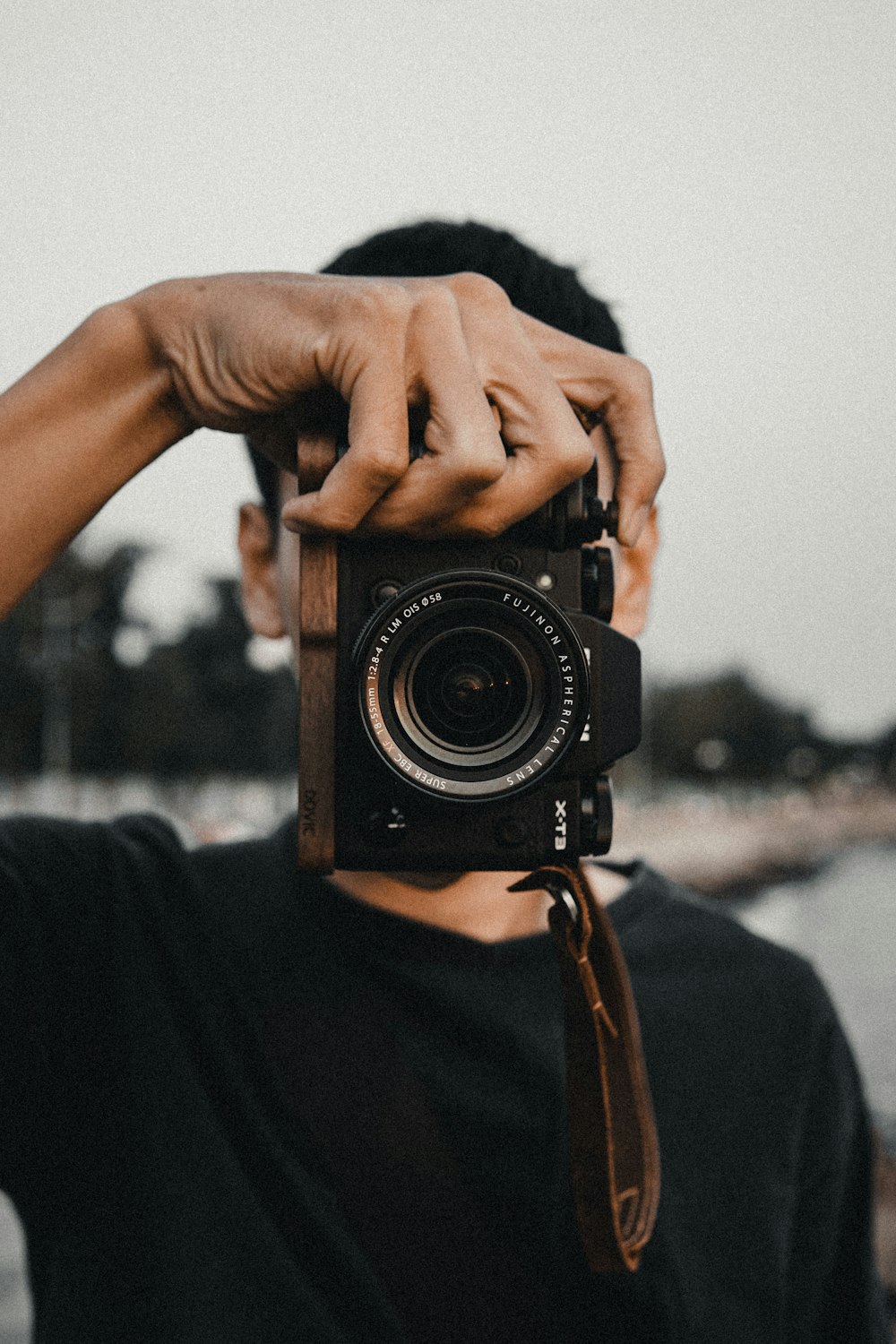 man in black crew neck shirt holding black nikon dslr camera