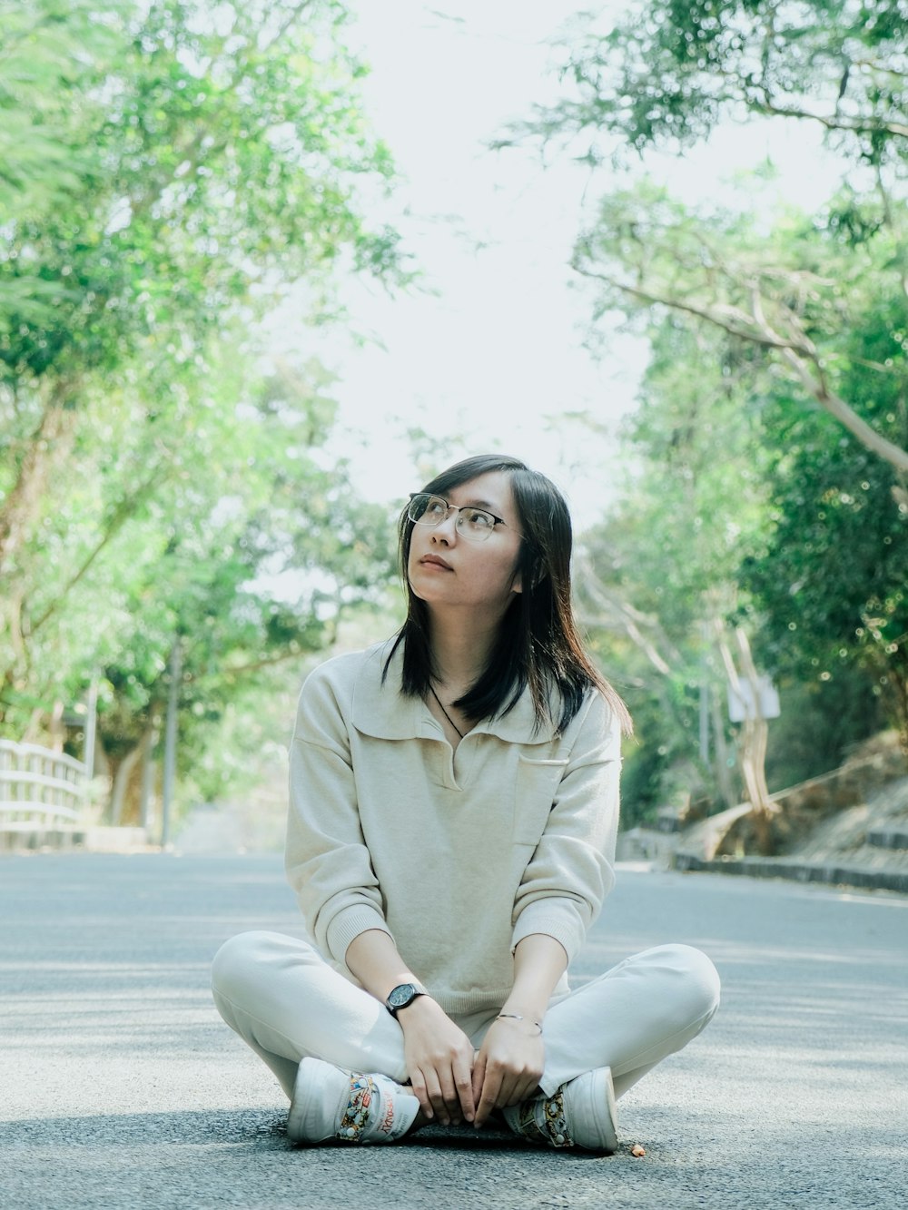 woman in beige coat sitting on the sidewalk during daytime