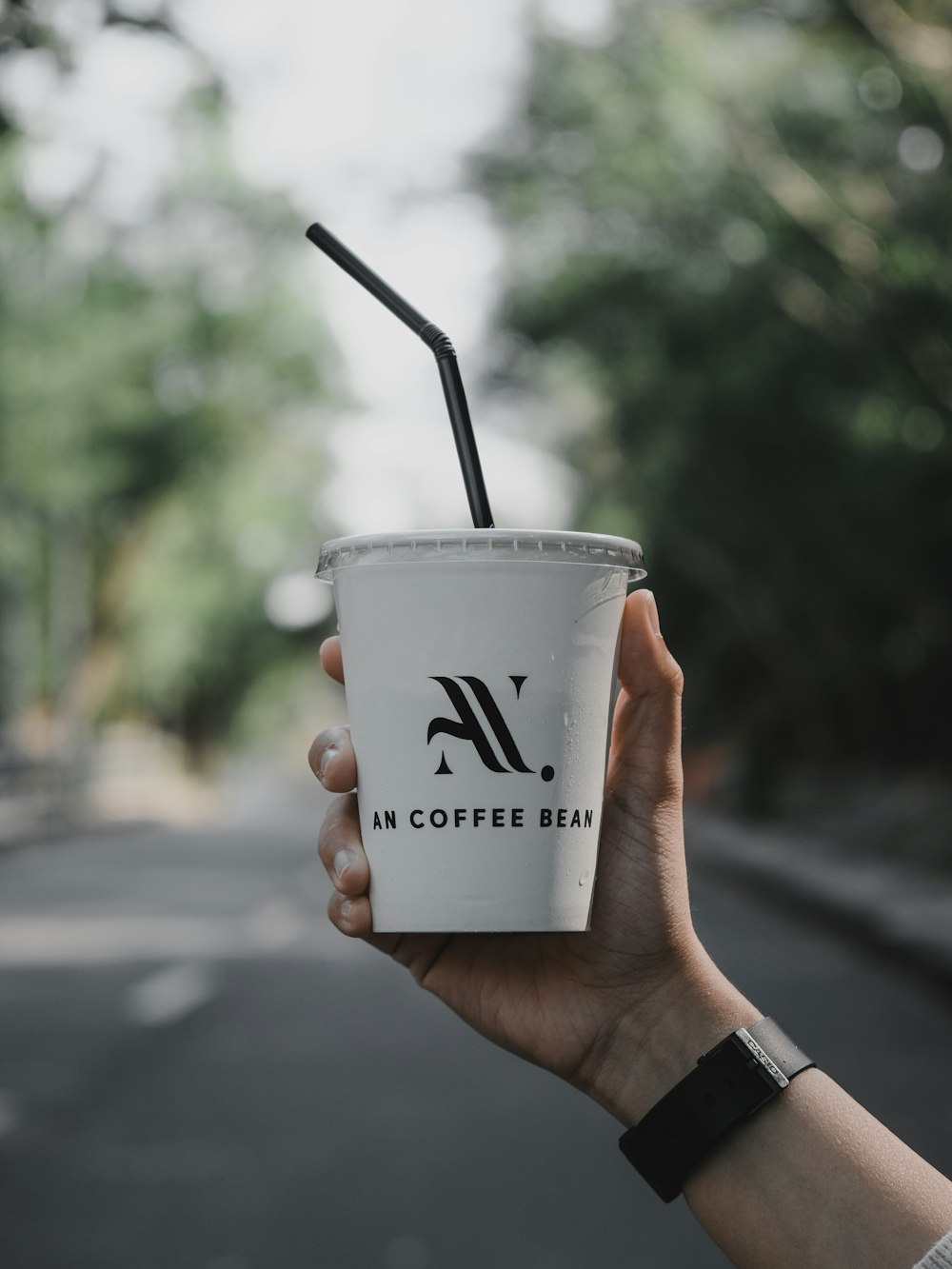 person holding white and black disposable cup with black straw