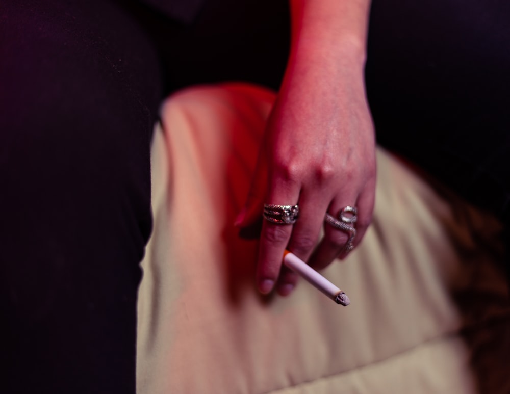 person wearing silver ring with white cigarette stick