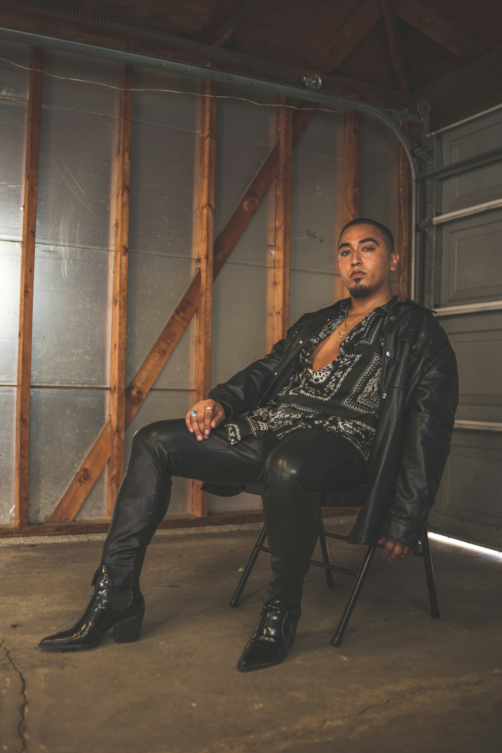 man in black leather jacket and black pants sitting on chair