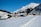 Snow-covered mountain village street with traditional alpine houses under a clear blue sky.