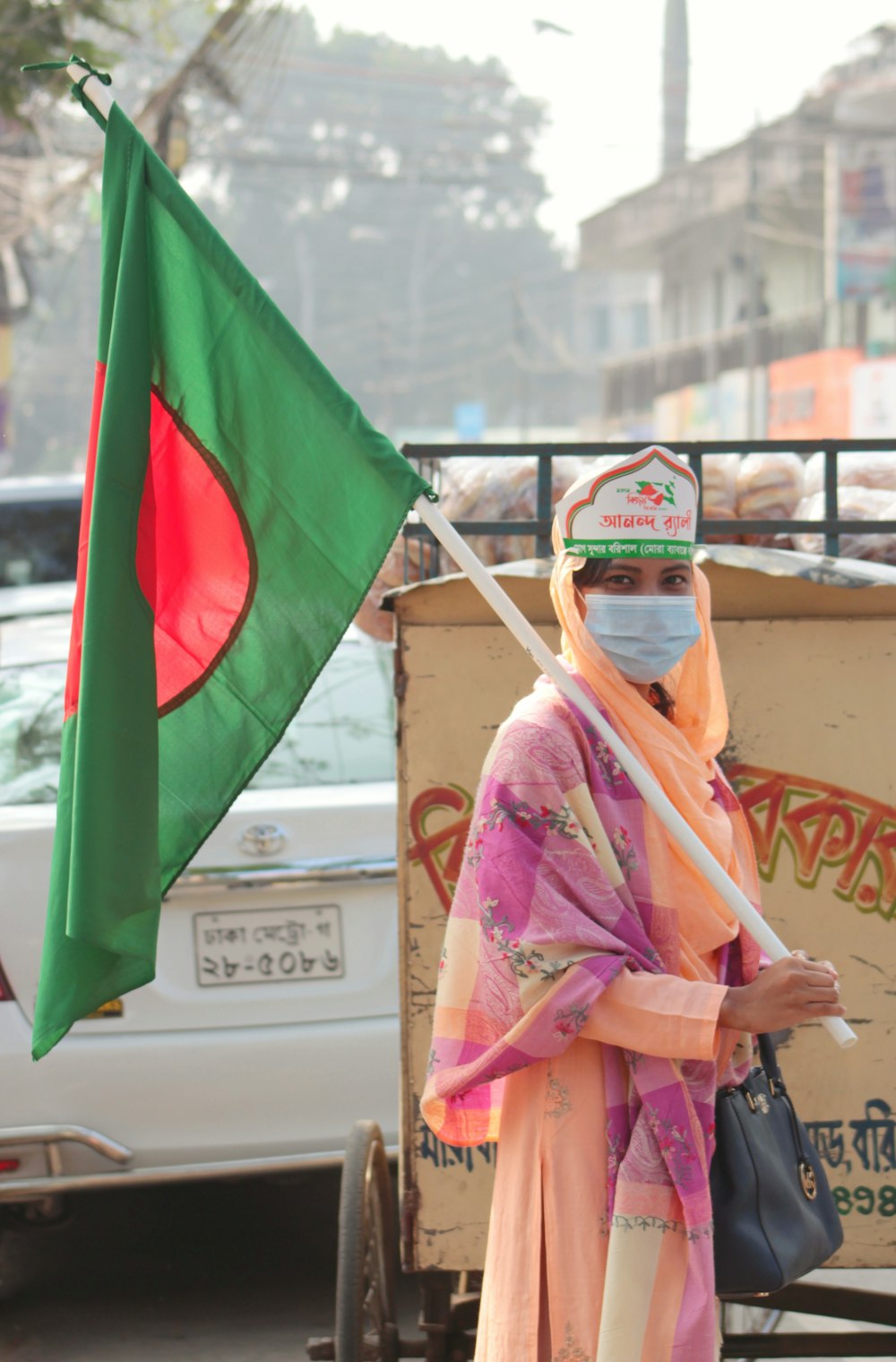 woman in pink and yellow hijab holding green flag