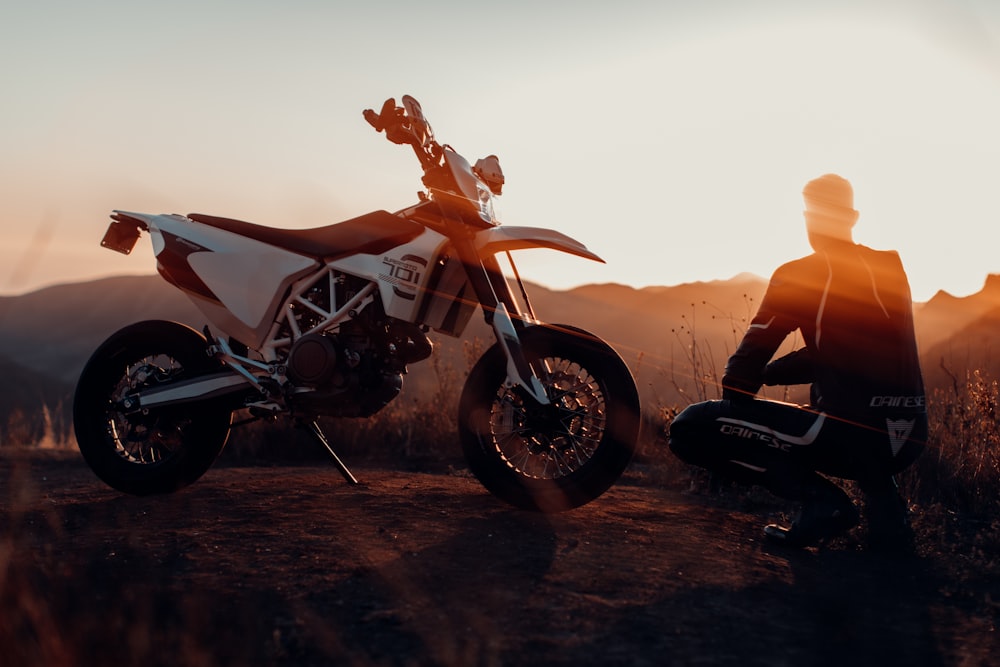 uomo in giacca nera seduto sulla motocicletta durante il tramonto