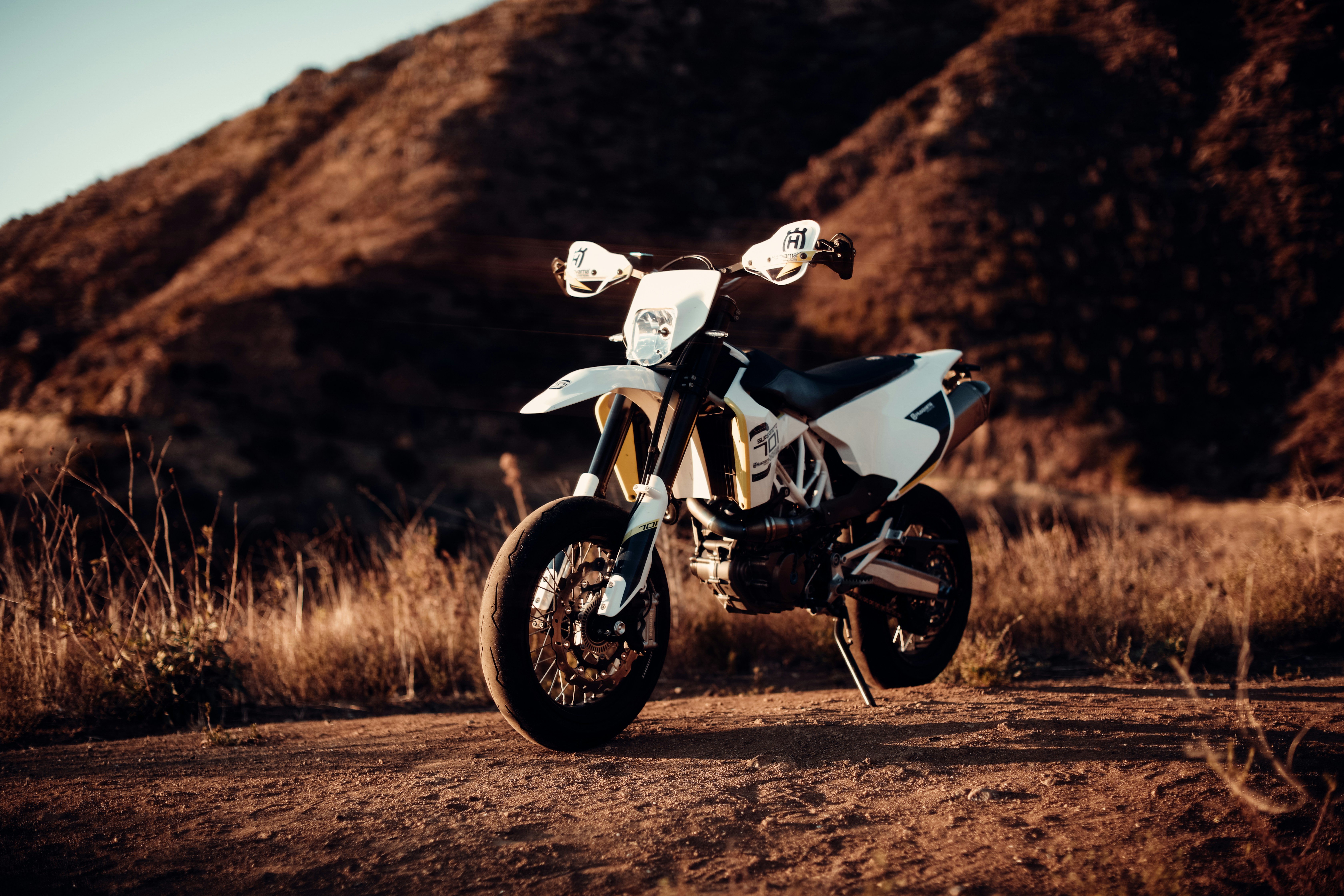 Husqvarna 701 supermoto posted up in the dirt.