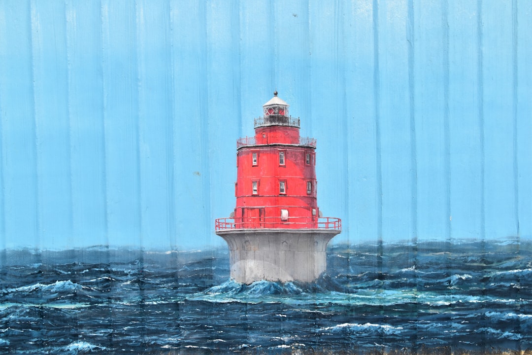 red and white lighthouse on body of water during daytime