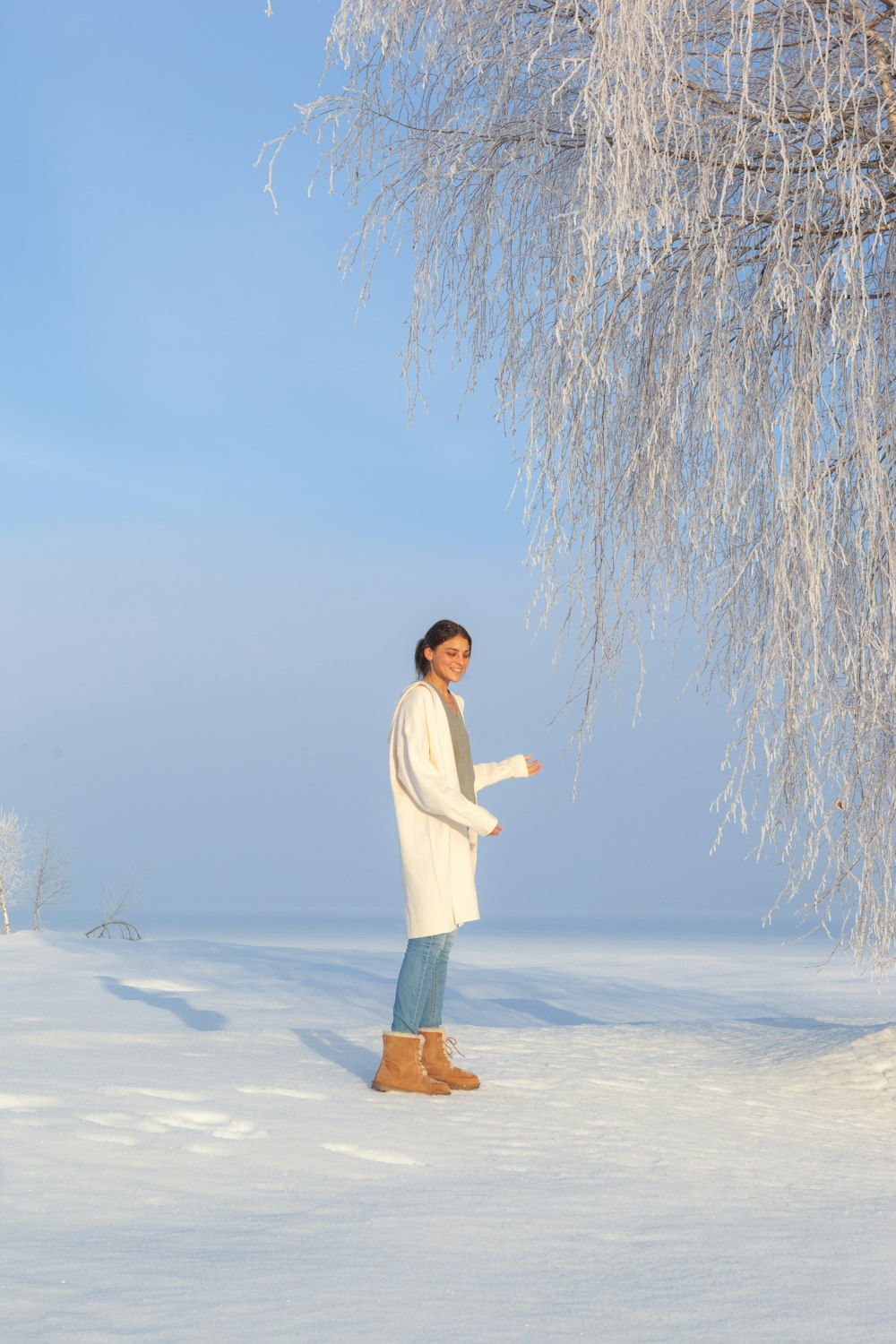 woman in white long sleeve shirt and brown skirt standing on snow covered ground during daytime