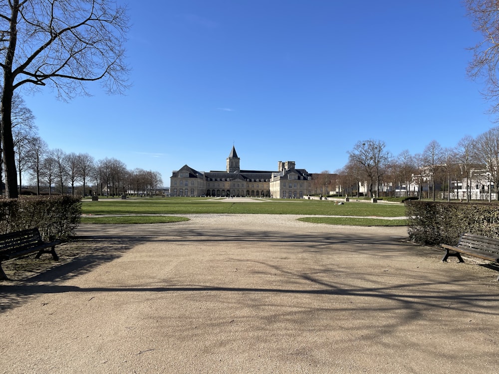 Grünes Grasfeld in der Nähe von grauem Betongebäude unter blauem Himmel tagsüber